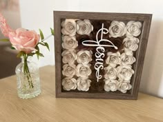 there is a vase with roses in it next to a framed sign that says love