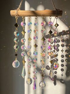 a wind chime hanging from a wooden stick next to a white curtain with beads on it