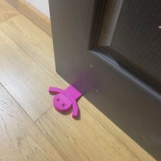 a pink dog shaped object sitting on the floor next to a wooden door frame and brown door