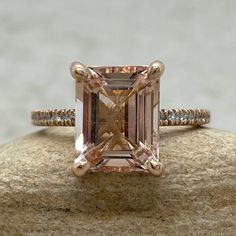 an engagement ring with a pink diamond in the center on top of a stone surface