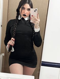 a woman taking a selfie in front of a mirror wearing a black dress and white collared shirt