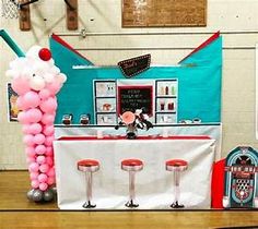 a table with balloons and stools in front of a basketball hoop on the floor