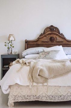 a bed with white sheets, pillows and blankets on top of it next to a night stand