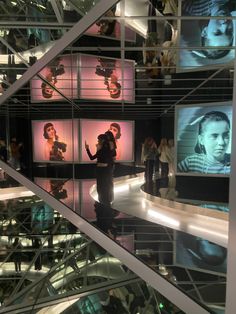 people are standing on the stairs in front of large screens with images of men and women