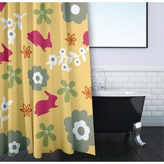 a bath tub sitting next to a shower curtain with flowers on it in a bathroom