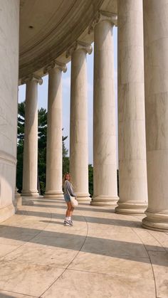 a woman is standing in front of some pillars