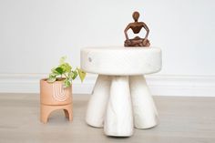 a small potted plant sitting on top of a white table next to a statue