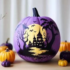 a purple pumpkin with a castle painted on it next to other pumpkins and decorations