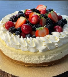 a cake with white frosting and fresh berries on top is sitting on a table