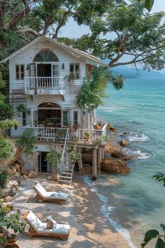 a house on the beach with lounge chairs and trees around it, overlooking the ocean