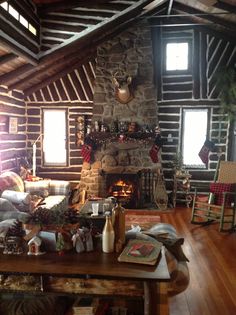 a living room filled with furniture and a fire place next to a stone fireplace in a log cabin