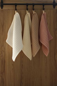 three towels hanging on a rail in front of a wooden wall