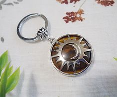 a metal keychain with a sun design on it