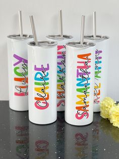 three personalized tumblers with straws in them on a table next to flowers