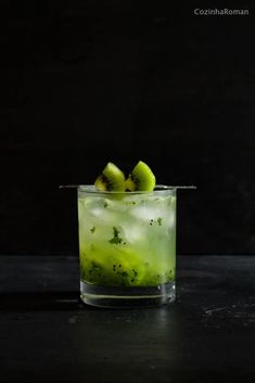 a green drink with kiwis in it sitting on a table next to a black background