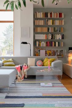 a living room filled with lots of furniture and bookshelves next to a window