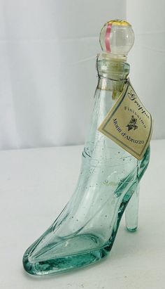 a glass shoe shaped bottle sitting on top of a table