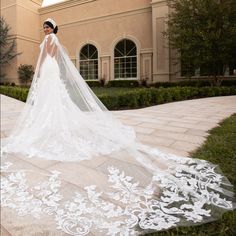 a woman in a wedding dress is standing on the sidewalk with her veil over her head