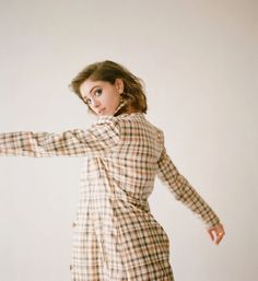 a woman in a plaid dress is posing for the camera with her arms spread out