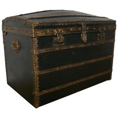 an old black trunk with gold trimmings on the top and bottom, sitting against a white background