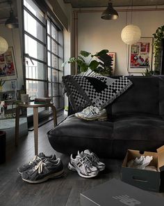 a living room filled with black furniture and lots of shoes on the floor in front of a window