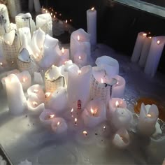 many white candles are lit on a table