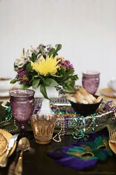 a table topped with lots of purple and yellow dishes filled with flowers on top of it