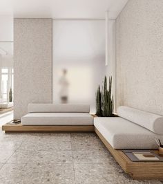 a living room filled with white couches next to a potted plant