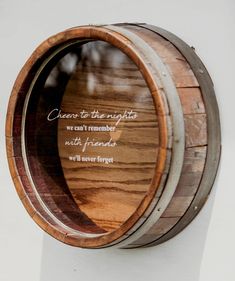 a wooden barrel with a quote on it sitting on top of a white wall next to a tree