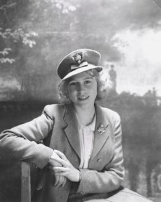 an old black and white photo of a woman wearing a hat sitting on a bench