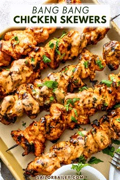 grilled chicken skewers on a platter with cilantro and parsley