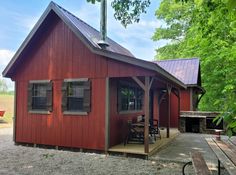 a small red building sitting in the middle of a forest next to a picnic table