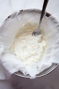 a spoon in a bowl with whipped cream on the top and white cloth around it