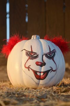 a white pumpkin with red hair painted on it's face sitting in the grass