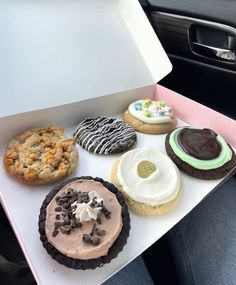 a person is holding a box filled with different types of cookies and pastries in it