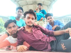 four young men sitting on the ground posing for a photo