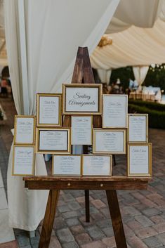 a wooden table topped with lots of framed pictures next to a white drape covered tent