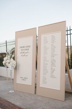 two framed signs with names on them sitting in front of a fence and flower arrangement