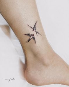 two birds flying in the air on top of a person's foot