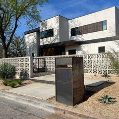 a modern house with an outdoor trash can in the front yard