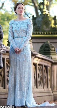 a woman in a blue dress standing on a bridge