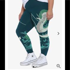 a woman in green leggings with a dragon on the side and white sneakers