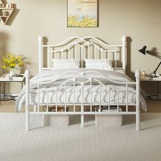 a white bed sitting in a bedroom on top of a carpeted floor next to a lamp