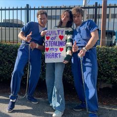 three people standing in front of a fence holding a sign that says, guilty of stealing my heart