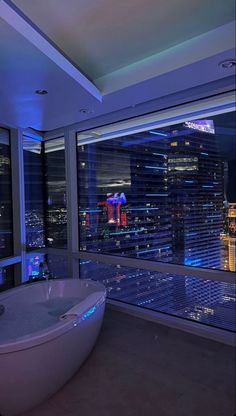 a bath tub sitting in front of a window next to a tall building at night