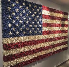 an american flag made out of shredded paper on display in a room with white walls