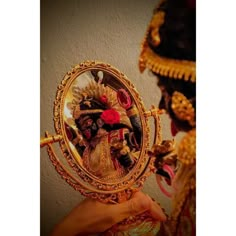 a close up of a person holding a mirror in front of their face with an ornate decoration on it