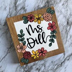 a wooden sign that says, ms bill with flowers around it on a marble surface