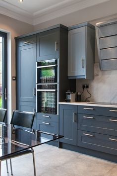 a modern kitchen with gray cabinets and glass top dining table in front of an open window