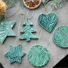 christmas ornaments made out of clay and decorated with leaves, oranges and pine cones